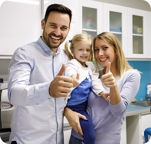 Smiling family giving thumbs-up at a dental office.