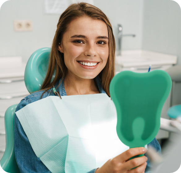 Smiling patient holding a mirror after dental treatment.