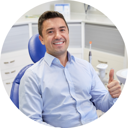 Smiling patient giving a thumbs-up in a dental chair.