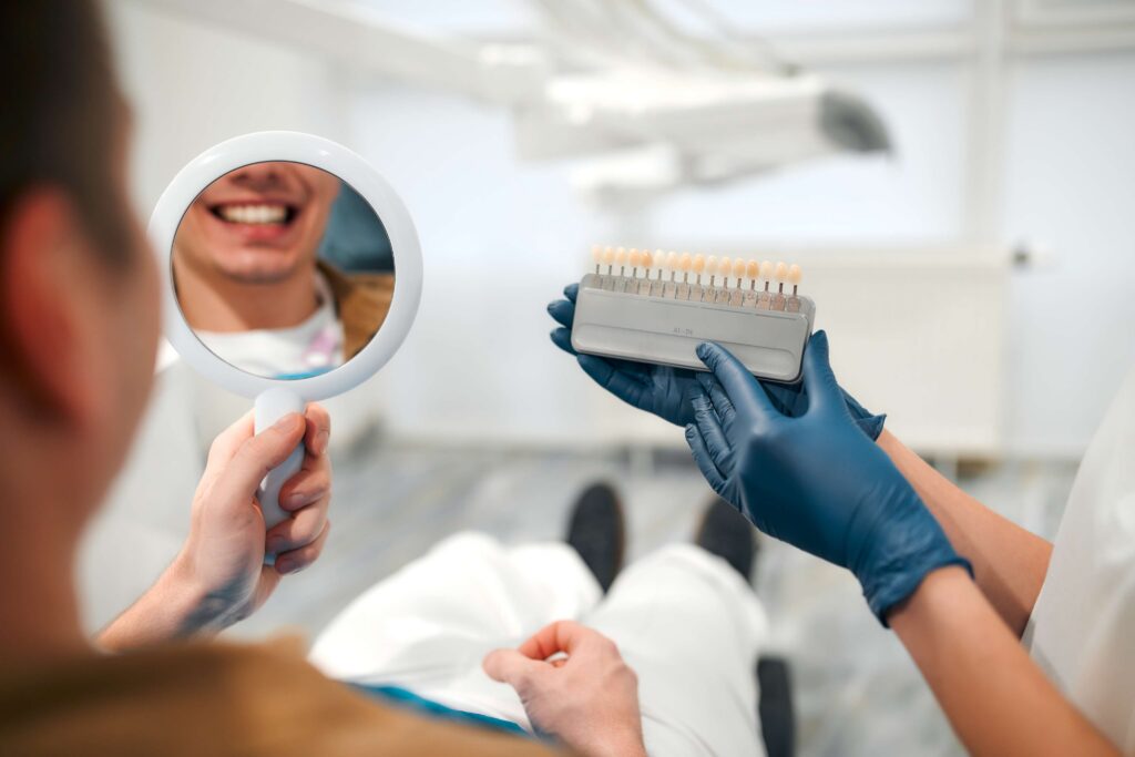 Patient comparing smile shades with a dentist.